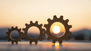 Wooden gears interlocked on a reflective surface at sunset, symbolizing teamwork and mechanical process