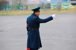 uniformed traffic officer in a blue coat and cap directs traffic with an outstretched arm