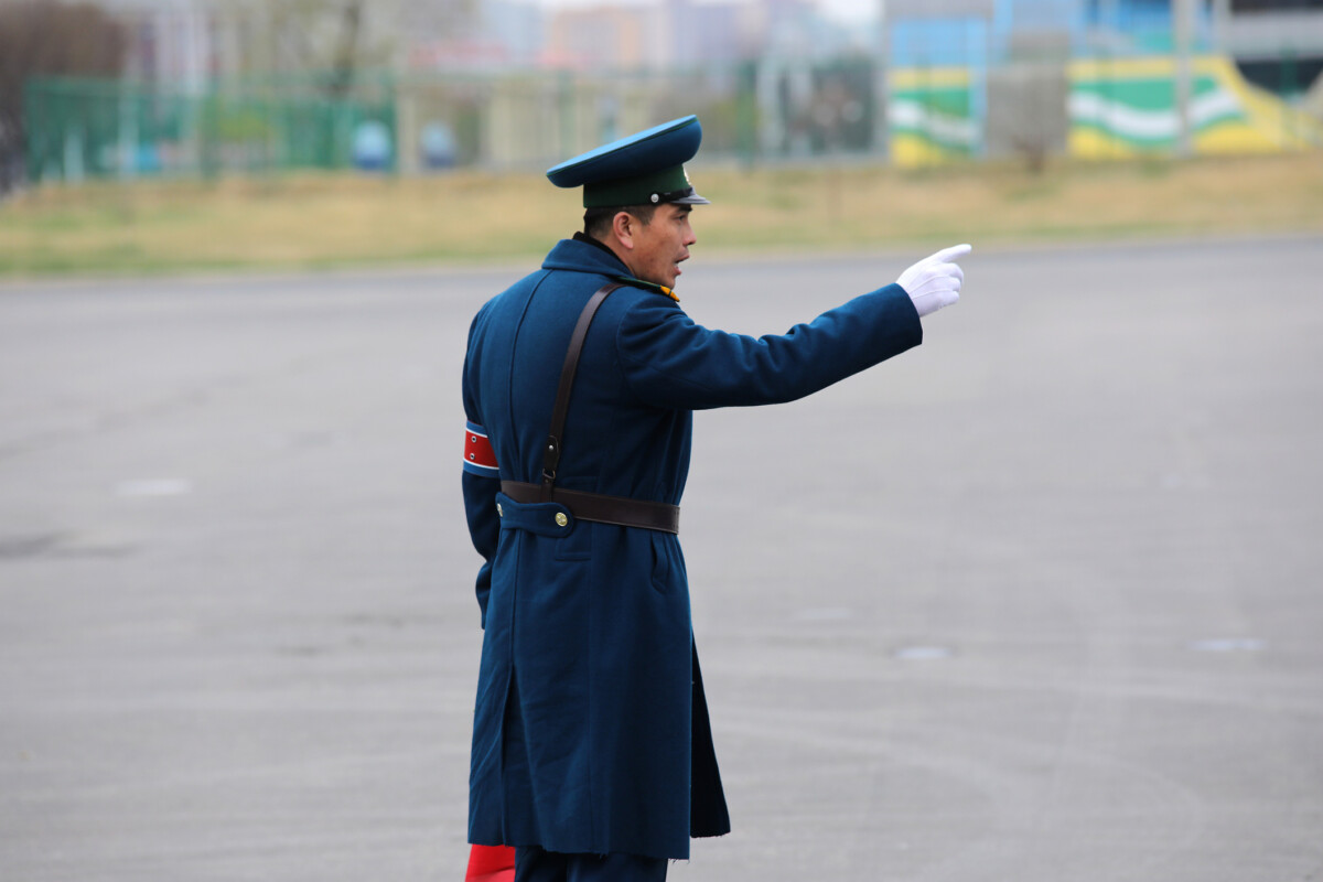 uniformed traffic officer in a blue coat and cap directs traffic with an outstretched arm