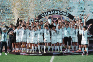 womens soccer team on a podium celebrating with trophy and medals as confetti falls