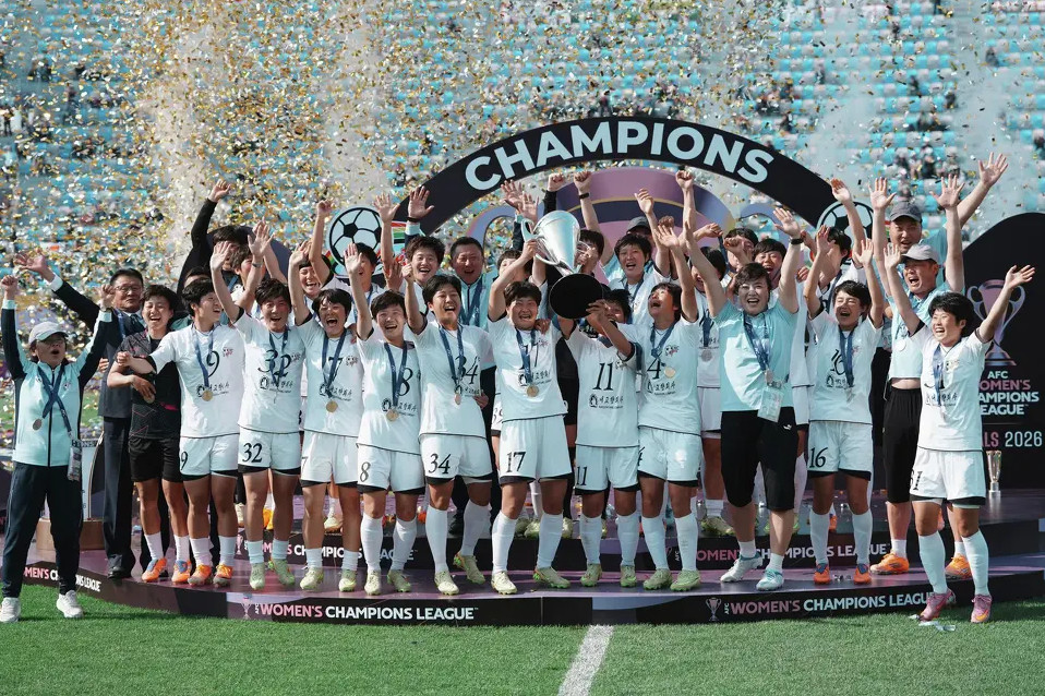 womens soccer team on a podium celebrating with trophy and medals as confetti falls