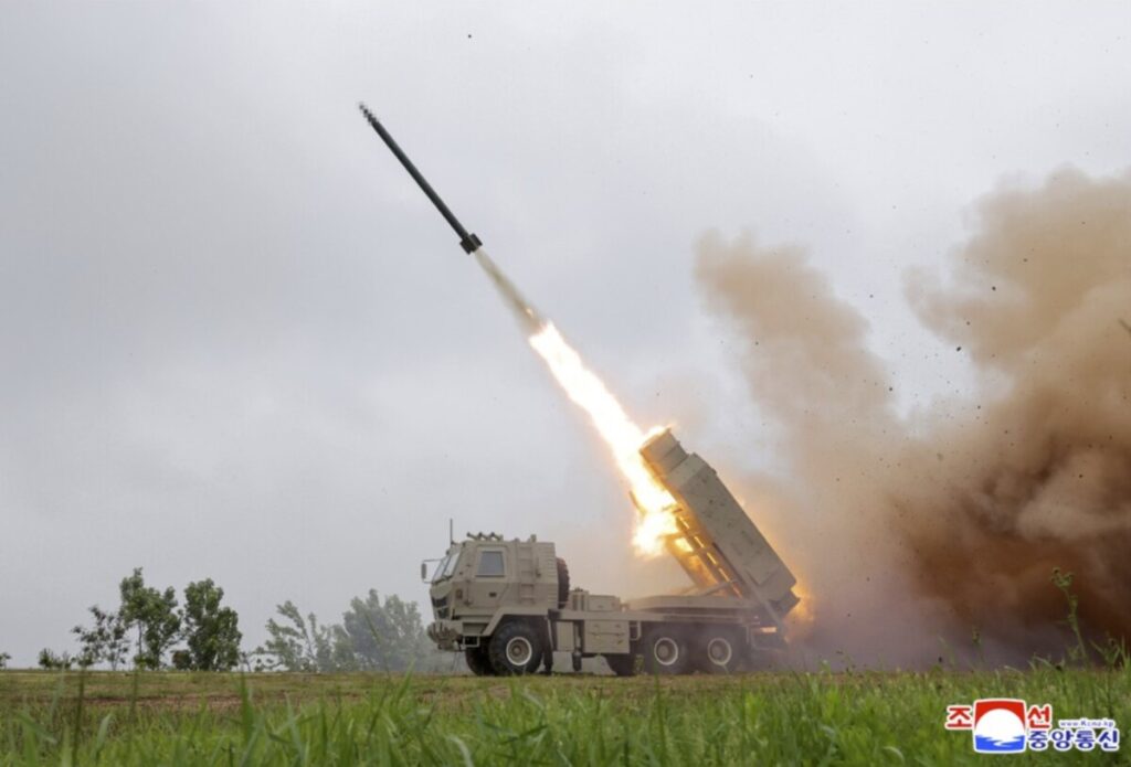 Kju at a missile test site 3 | nk insider military truck mounted rocket launcher firing a rocket into the sky flames and smoke billowing from the launcher on a grassy field in overcast weather