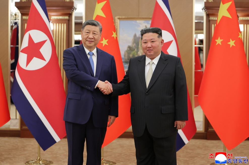 Xk | nk insider two men in suits shake hands in a formal setting with north korean and chinese flags behind them