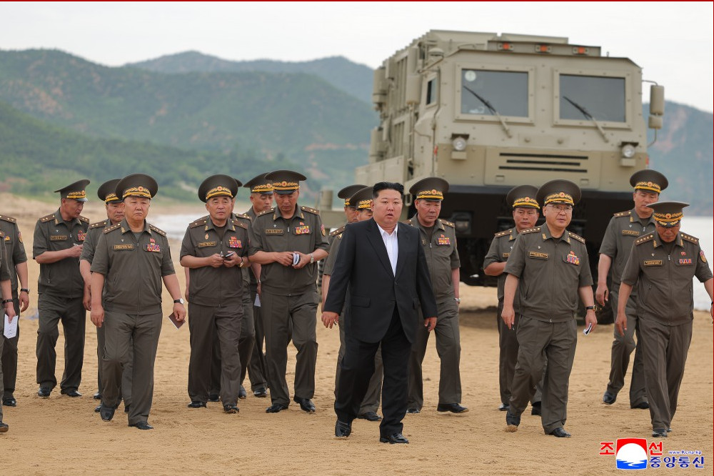 화면 캡처 20260703 203638 | nk insider group of uniformed military officers walking on a sandy beach with a large armored vehicle parked behind them