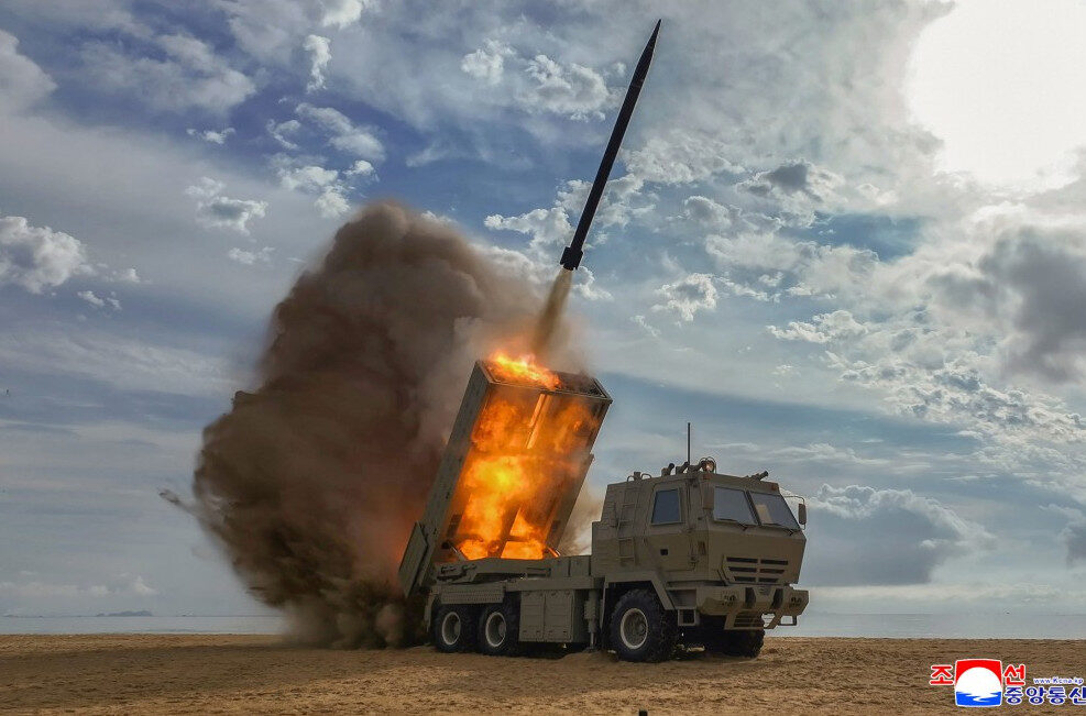 missile launch from a desert terrain with a launcher vehicle firing and a large orange flame and smoke plume