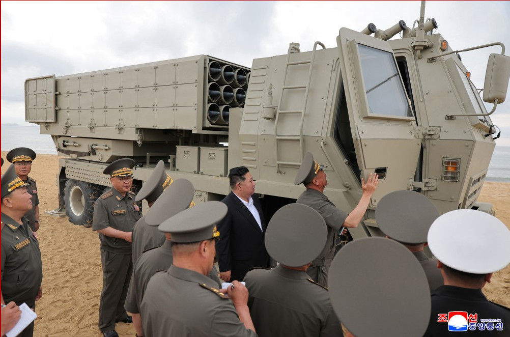 화면 캡처 20260704 000047 | nk insider uniformed officials inspect a large beige mobile missile launcher on a sandy beach near the sea