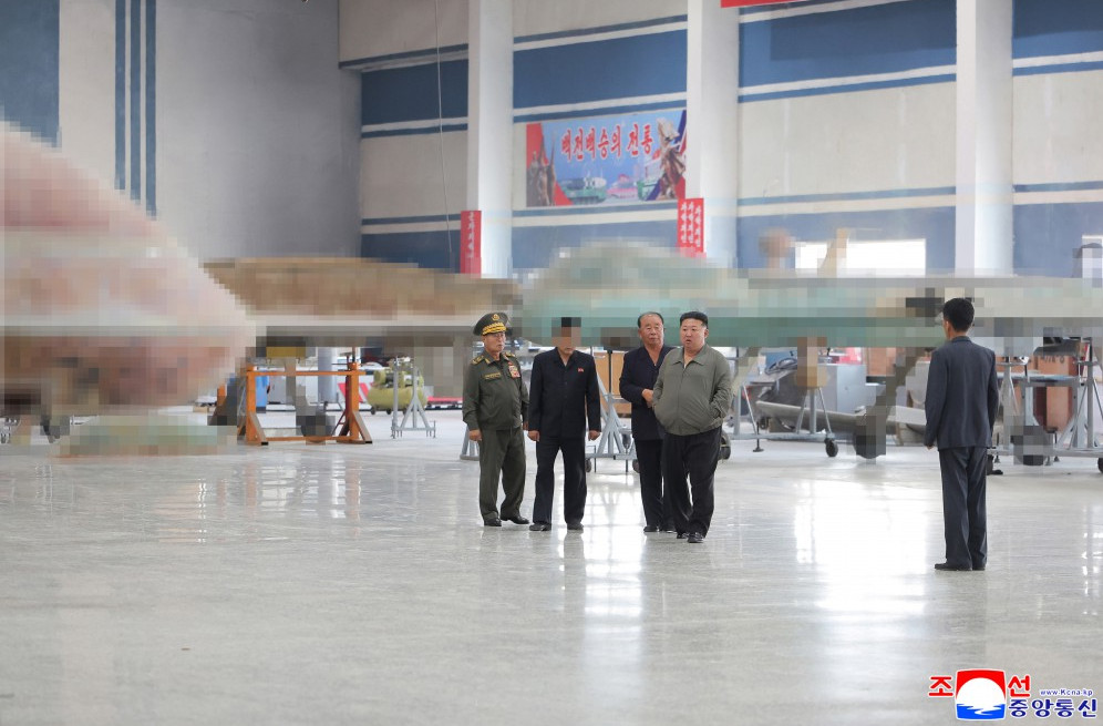 11 | nk insider group of men including a uniformed officer standing in a spacious aircraft hangar inspecting a large aircraft under maintenance